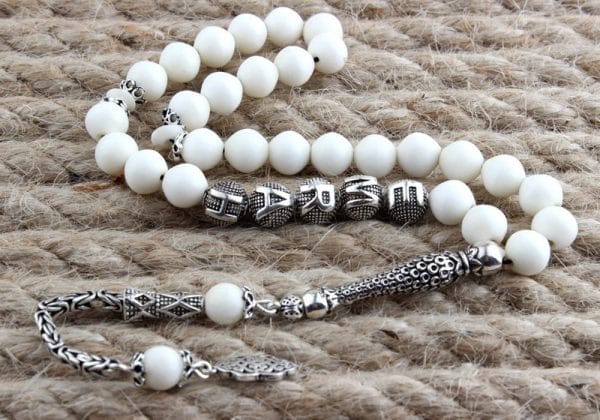 A rosary made of camel bone with a silver tassel, engraved with the name
